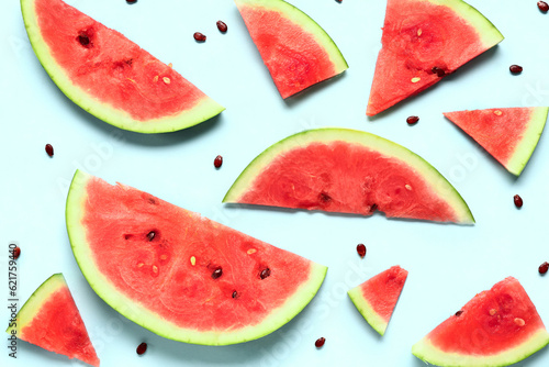 Pieces of fresh watermelon and seeds on blue background
