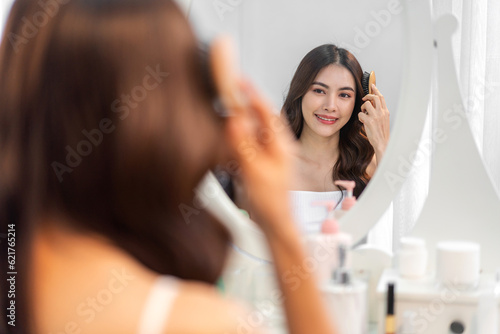 Smiling of beautiful asian woman fresh healthy white skin, clean, looking at mirror.asian girl touching on face applying cream, skincare, cosmetics, cosmetology, beauty, fashion at home.spa, wellness