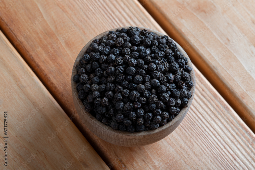 Bowl full of black pepper on a wooden background,top view Bowl full of black pepper on a wooden background,top view