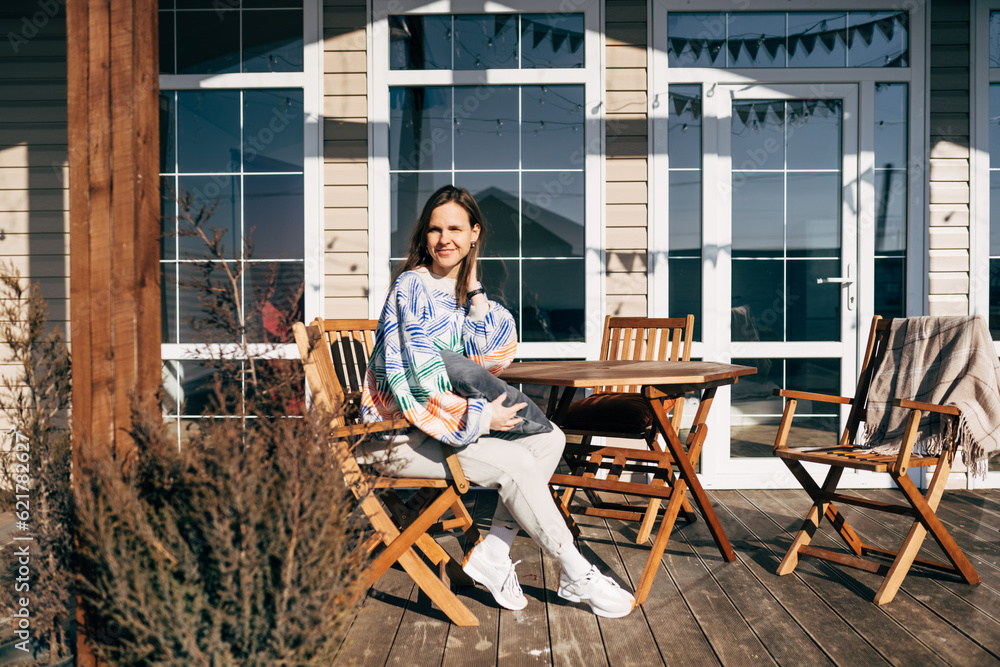 Woman standing near tables at cafe and keeping smartphone, wearing jeans shirt. oncept of fashion look and catering establishment. Woman standing near tables at cafe and keeping smartphone, wearing jeans shirt. oncept of fashion look and catering establishment.