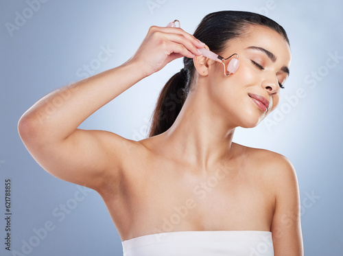 Billede på lærred Skincare, derma roller and asian woman in studio for anti aging, cosmetic or face massage on grey background