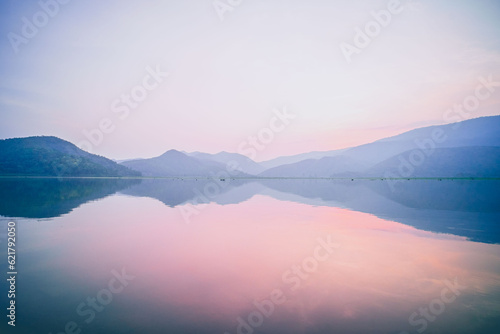 A Serene Panorama of Mountain Lake Reflecting on Water with a Pink Pastel Romantic Sky at Dusk © Parichart