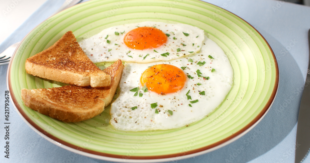 fried eggs with toast on a green plate. close-up. angle view. camera tracking. white background. traditional breakfast. sunny day.