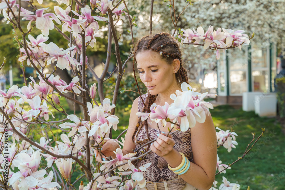 Magnolia flowers. Happy woman enjoys by blooming magnolia tree and sniffs it flowers with closed eyes in spring garden. Portrait. Magnolia flowers. Happy woman enjoys by blooming magnolia tree and sniffs it flowers with closed eyes in spring garden. Portrait.