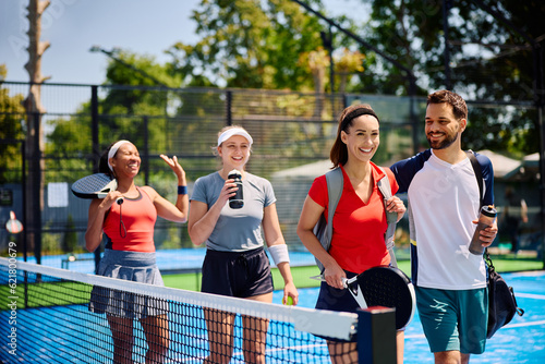 Multiracial group of athletes going for an outdoor mixed doubles match in paddle tennis. photo