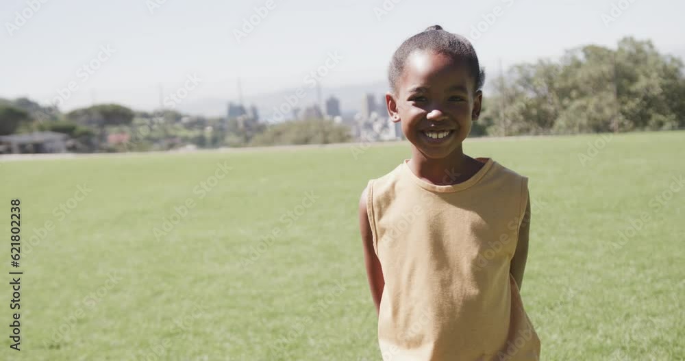 Portrait of happy african american girl on sunny elementary school field, copy space, slow motion