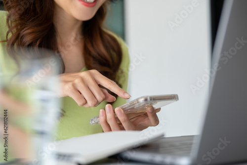 Young woman engaged in online study or project work with smartphone.