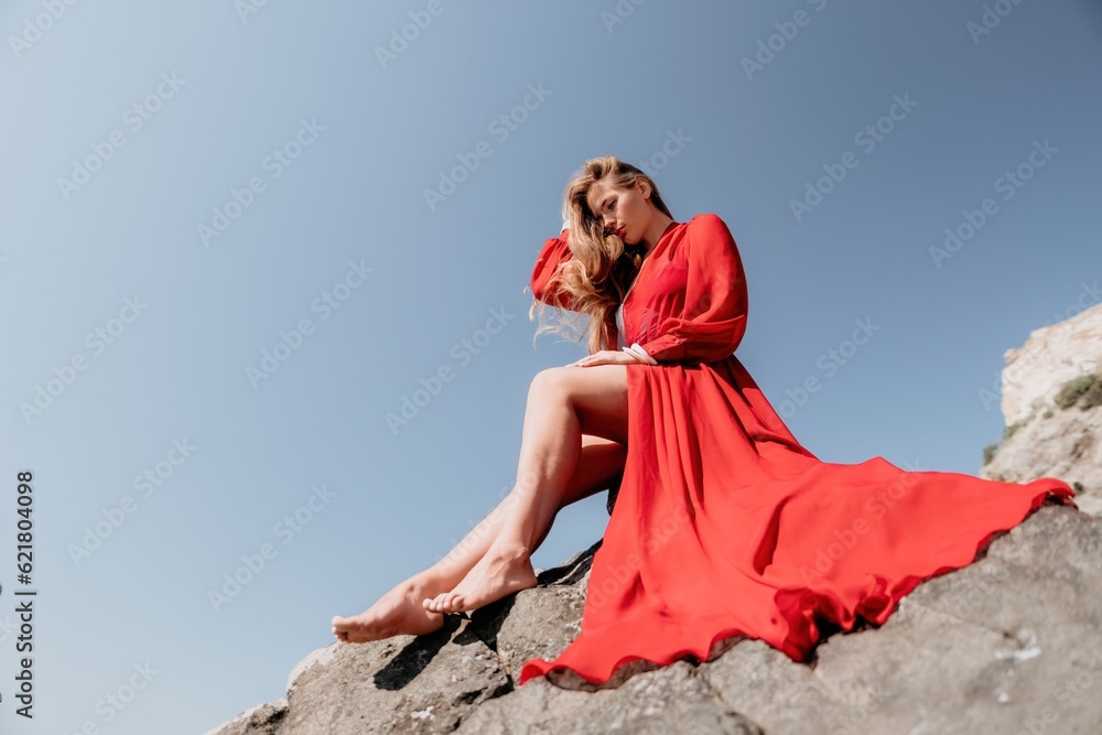 Woman travel sea. Young Happy woman in a long red dress posing on a beach near the sea on background of volcanic rocks, like in Iceland, sharing travel adventure journey Woman travel sea. Young Happy woman in a long red dress posing on a beach near the sea on background of volcanic rocks, like in Iceland, sharing travel adventure journey