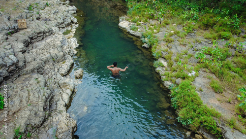 young man alone swimming in a clean and beautiful river