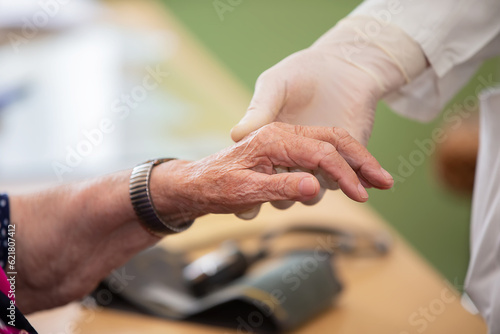 The hand of the doctor holds the hand of the old man. Close-up of a doctor and the trembling hand of a disabled elderly woman. Human aging concept.