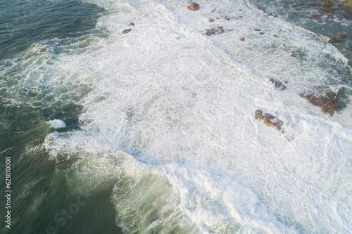 top aerial view of foamy waves on a rocky shore