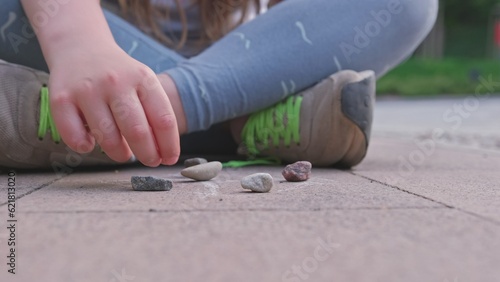 Caucasian Girl Mastering Dexterity Game of Jackstones Scatter Jacks Knucklebones using Small Rocks
