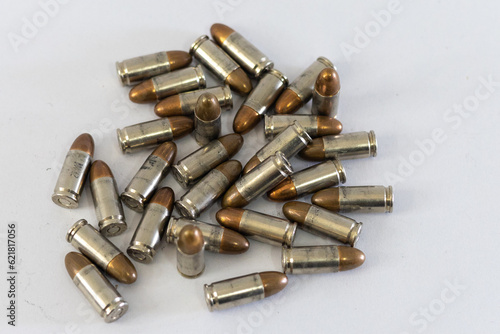 Pile of golden 9mm pistol bullets on a white background
