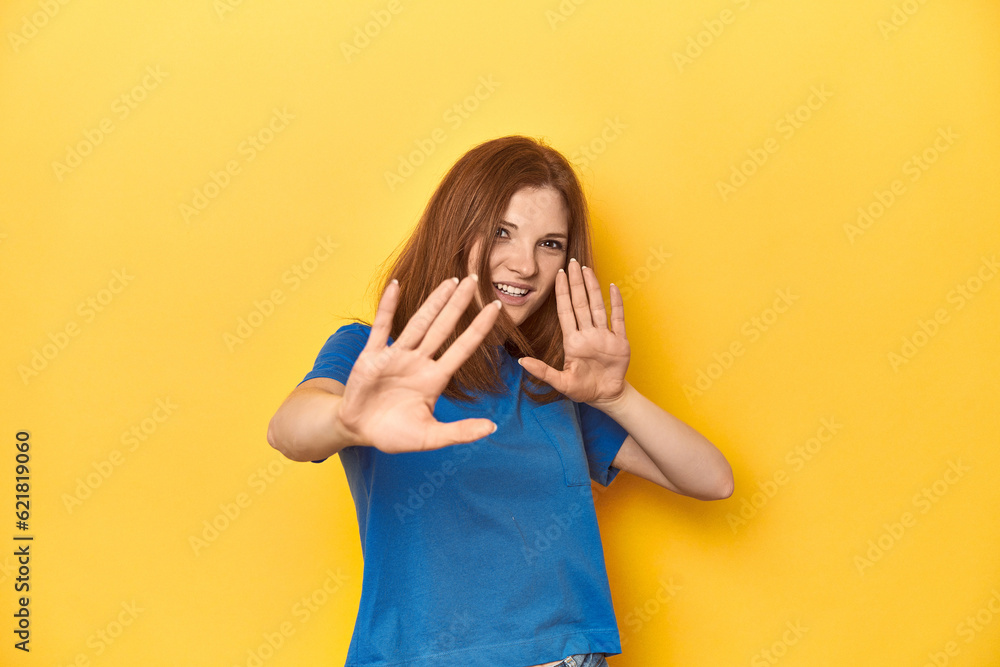 Redhead in blue t-shirt on yellow backdrop being shocked due to an imminent danger Redhead in blue t-shirt on yellow backdrop being shocked due to an imminent danger
