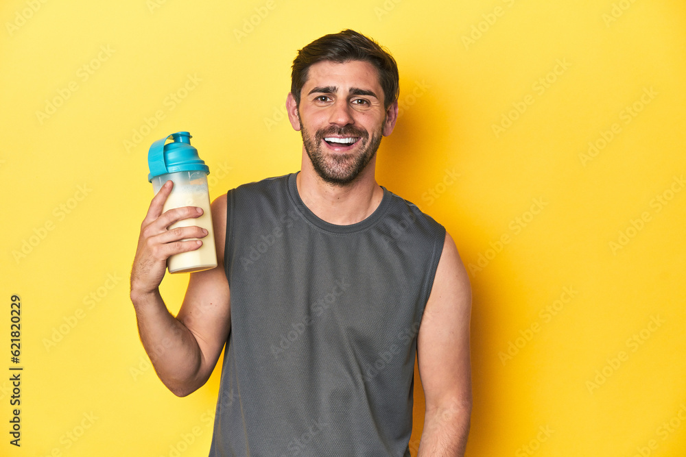 Fit man with protein shake, yellow studio background happy, smiling and cheerful. Fit man with protein shake, yellow studio background happy, smiling and cheerful.