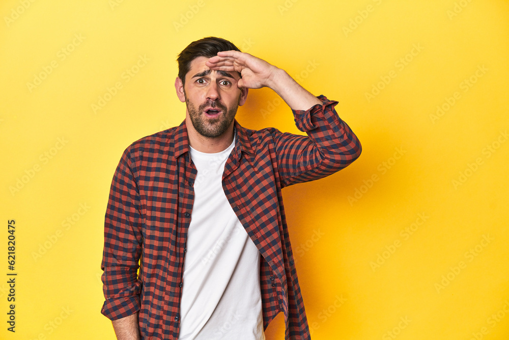 Caucasian man in red checkered shirt, yellow backdrop shouts loud, keeps eyes opened and hands tense. Caucasian man in red checkered shirt, yellow backdrop shouts loud, keeps eyes opened and hands tense.