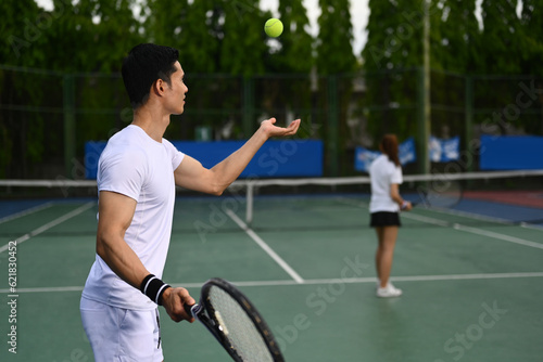 Shot of male tennis player with racket serving ball during match. Outdoor sports and healthy lifestyle concept