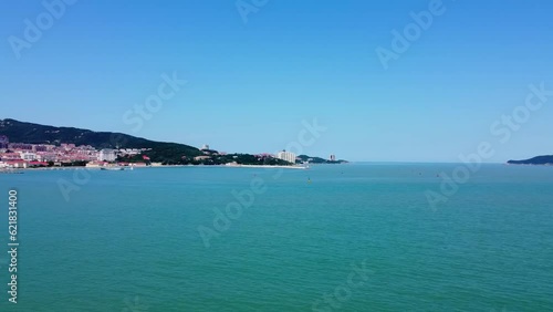 Aerial panorama shot of the beautiful blue sea off the coast of weihai city, china at xingfu park with a view of the city buildings in asian architecture on a sunny summer day photo