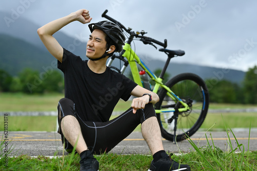 Handsome man in sport clothes taking a break from cycling bike in the morning. Outdoor sport activity and healthy lifestyle concept