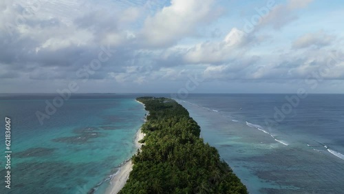 Vertical aerial along Dhigurah island in the Maldives, a long sandbank covered in lush tropical vegetation of coconut palm trees. photo