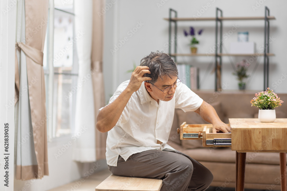 Asian older man finding something that he forgot it in drawers. Asian older man finding something that he forgot it in drawers.