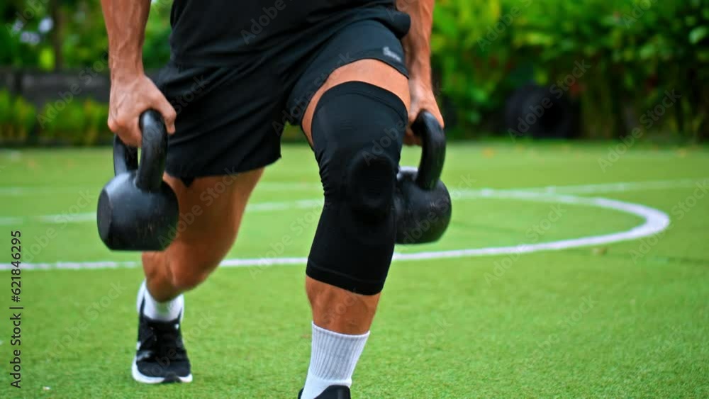 European athlete lifting weights on green grass, with the support of a knee brace for hand. Focuses on fitness, training, strength, and muscle development. European athlete lifting weights on green grass, with the support of a knee brace for hand. Focuses on fitness, training, strength, and muscle development.