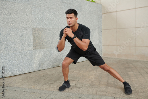 Fit man doing side lunges when working out outdoors