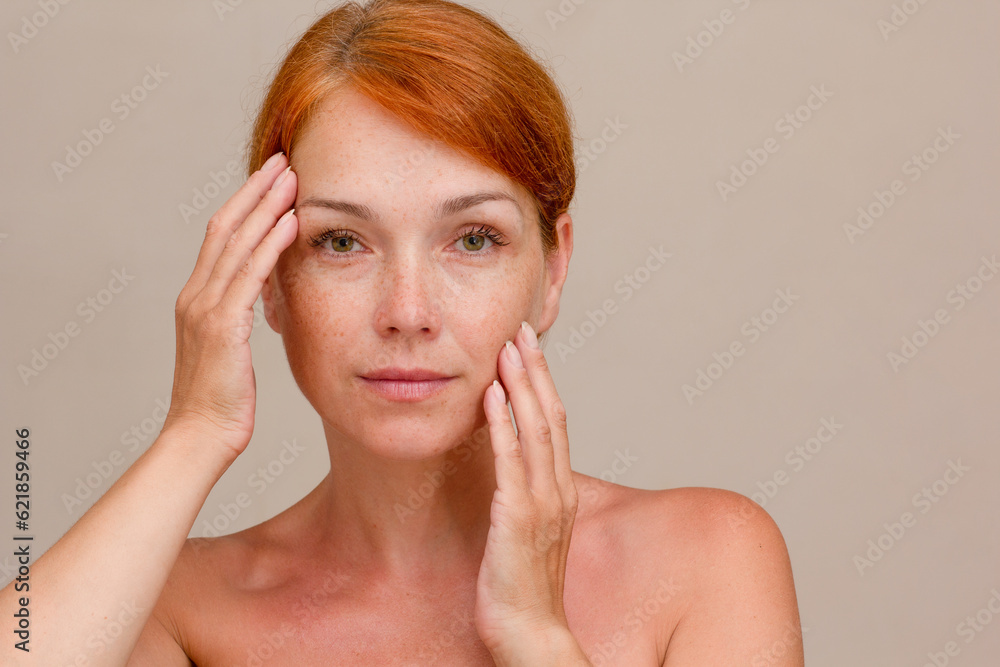 Portrait of cropped caucasian middle aged woman face with freckles holding fingers on cheek showing soft skin Portrait of cropped caucasian middle aged woman face with freckles holding fingers on cheek showing soft skin