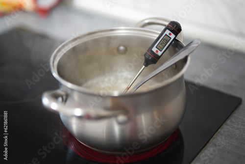 a pan on an electric stove and a thermometer measures the temperature