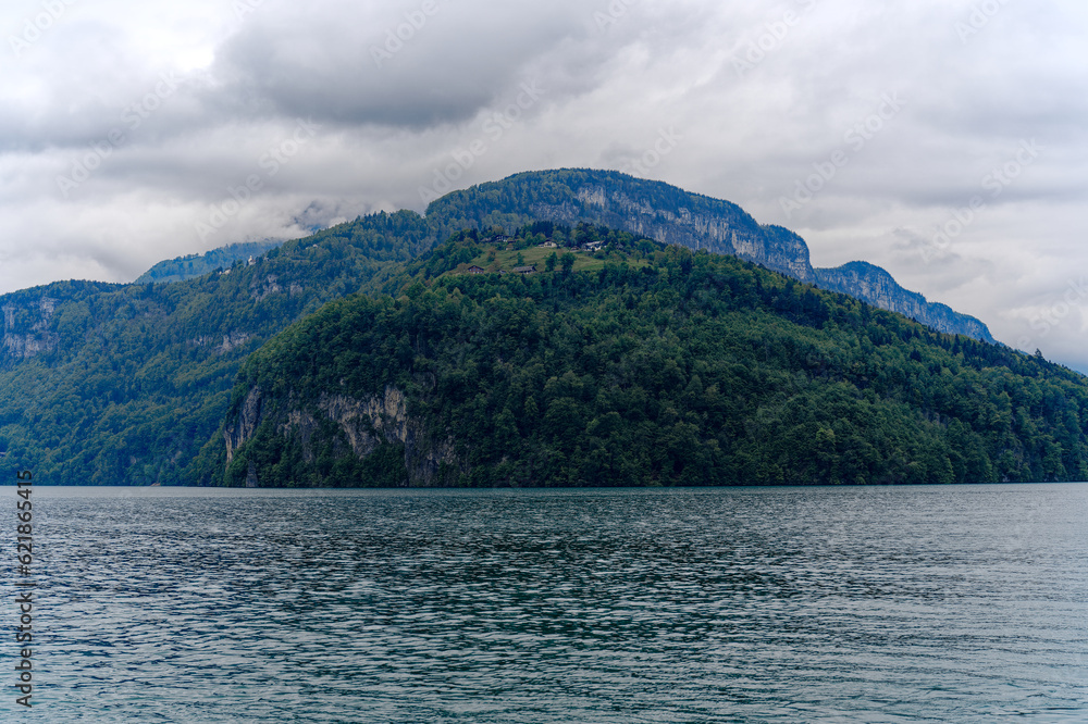 Scenic landscape with cliff and woodland at lakeshore of Lake Lucerne seen from passenger ship on Lake Lucerne on a cloudy spring day. Photo taken May 18t, 2023, Treib, Canton Uri, Switzerland.