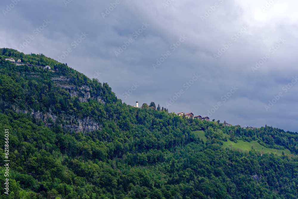 Scenic landscape with rock, cliff and woodland with mountain village Seelisberg at lakeshore of Lake Uri on a cloudy spring day. Photo taken May 18th, 2023, Seelisberg, Switzerland.