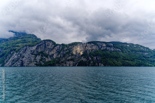 Scenic landscape with cliff and woodland at lakeshore of Lake Lucerne seen from passenger ship on Lake Lucerne on a cloudy spring day. Photo taken May 18t, 2023, Treib, Canton Uri, Switzerland. 