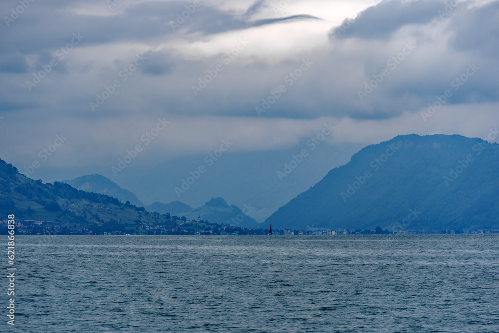 Scenic view of Lake Lucerne with mountain panorama and woolland in the background on a cloudy spring day. Photo taken May 18th, 2023, Treib, Switzerland.