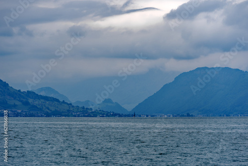 Scenic view of Lake Lucerne with mountain panorama and woolland in the background on a cloudy spring day. Photo taken May 18th, 2023, Treib, Switzerland.