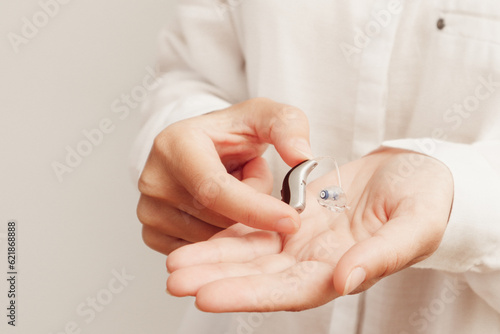 Hearing aids. Young Female Doctor Showing Hearing Aid To Patient