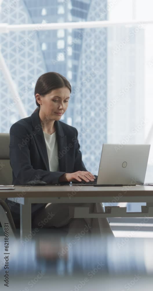 Verstical Screen: Professional Female CEO Typing On Laptop Computer In Bright Big City Office. Caucasian Woman Working In Meeting Room Of Investement Management Firm, Looking For Startups to Invest. Verstical Screen: Professional Female CEO Typing On Laptop Computer In Bright Big City Office. Caucasian Woman Working In Meeting Room Of Investement Management Firm, Looking For Startups to Invest.