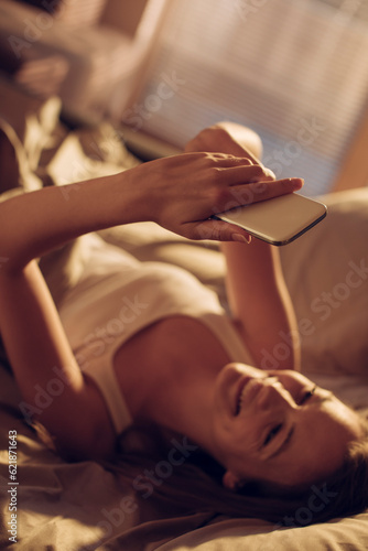 Young woman using a smart phone in the bed in the bedroom