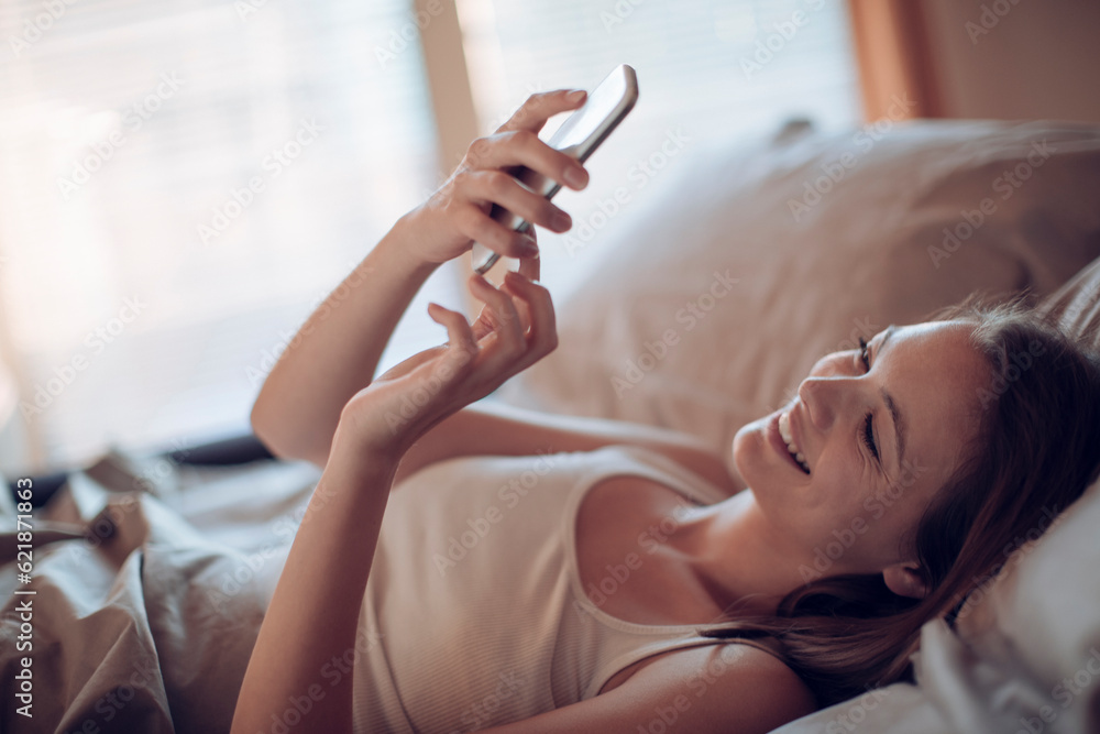 Young woman using a smart phone in the bed in the bedroom Young woman using a smart phone in the bed in the bedroom