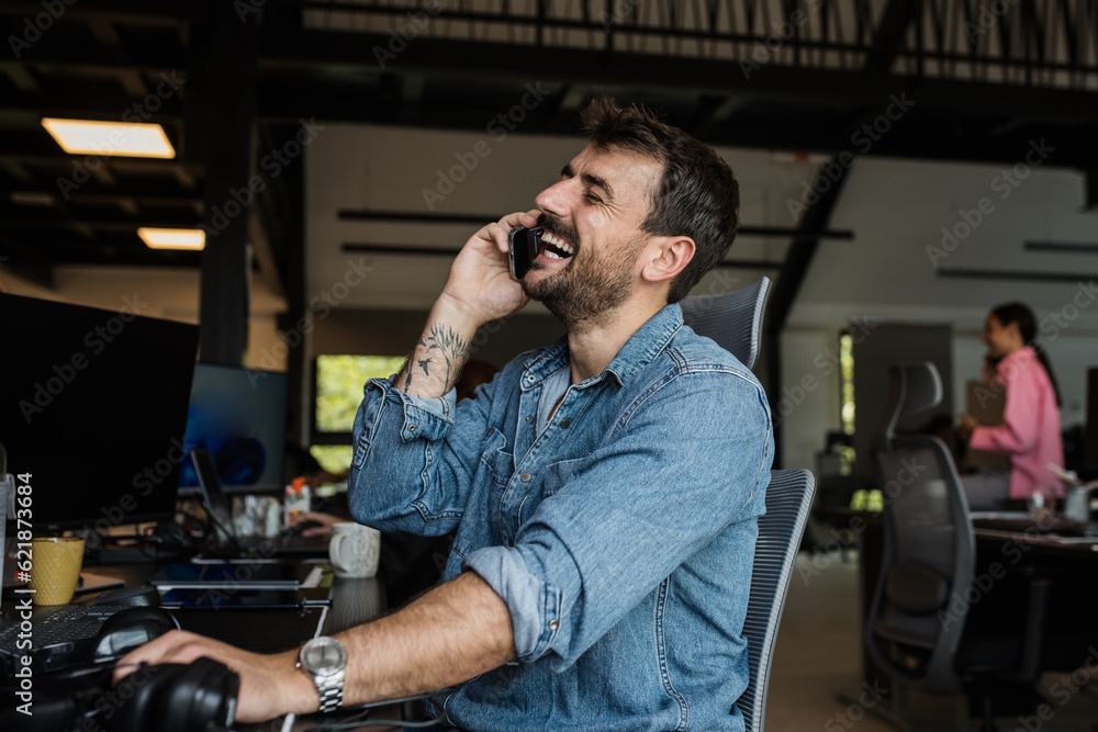 Smiling man talking on the phone in office Smiling man talking on the phone in office