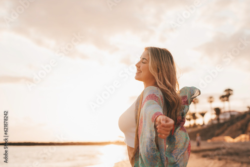 Portrait of one young woman at the beach with openened arms enjoying free time and freedom outdoors. Having fun relaxing and living happy moments.. #621878242