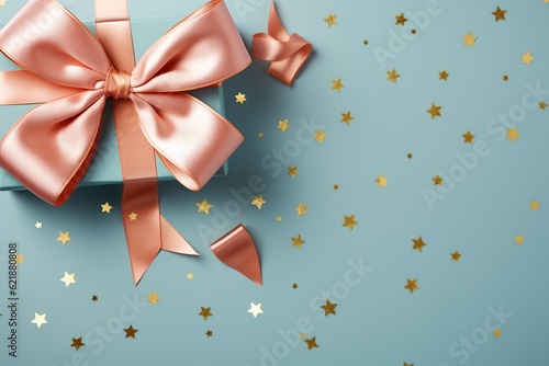 beige ribbon bow on kraft paper gift box over big shiny sequins on isolated blue background with copy space 