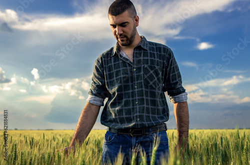 Portrait of young farmer walking in a green wheat field at sunset. © Zoran Zeremski