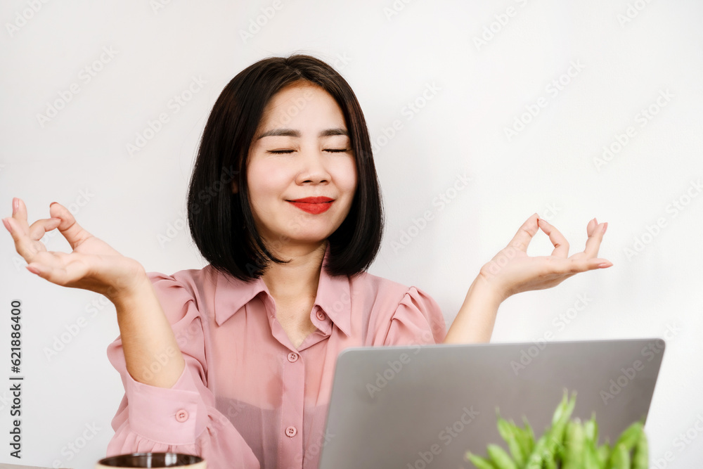 wellbeing Asian woman doing meditation at office desk to relief stress and relaxing and resting from work wellbeing Asian woman doing meditation at office desk to relief stress and relaxing and resting from work