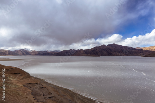 Pangong Lake transforms into a frozen wonderland in late March 2023. The icy surface reveals intricate cracks, adding a stunning texture to the landscape