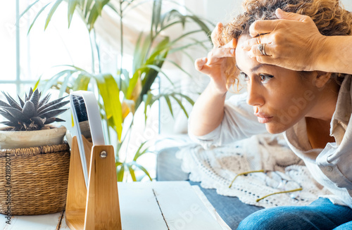 One adult lady at home touching front skin checking for age wrinkles.  in front of a little mirror on the table. Concept of aging woman. Female people worried about aging and skin care. Side view photo