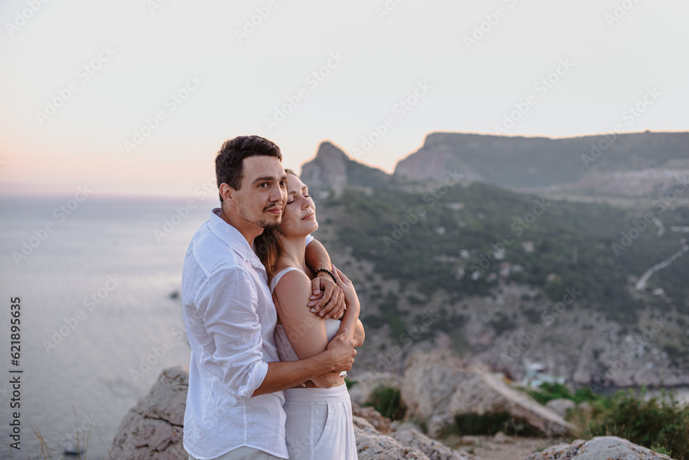 Beautiful young loving couple man of Middle Eastern appearance and a Caucasian woman hug, kiss at sunrise.