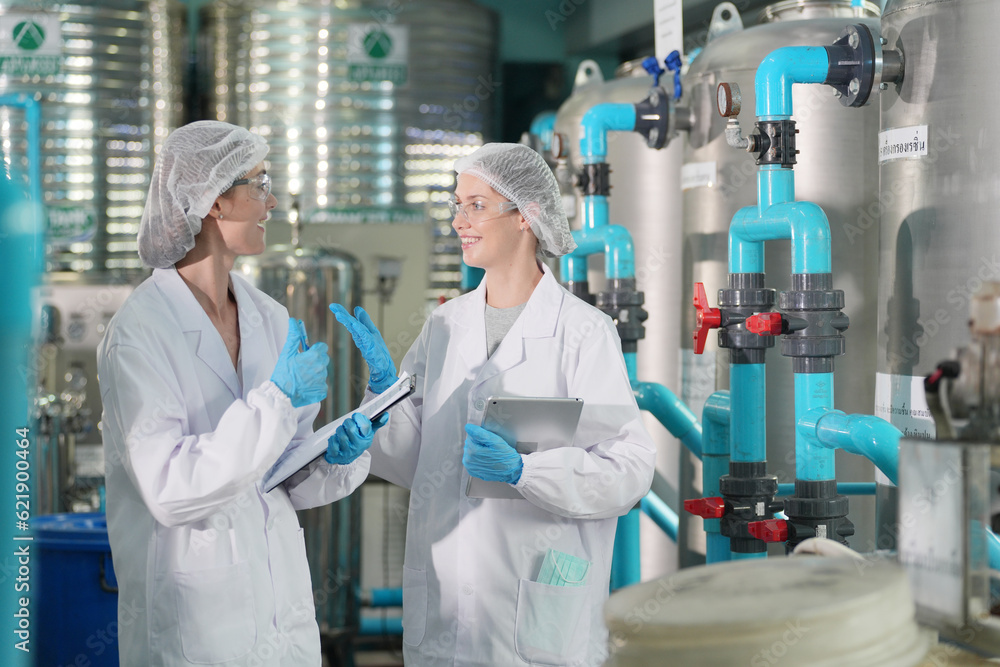 Female worker inspecting water bottle on production line in spring water factory Female worker inspecting water bottle on production line in spring water factory