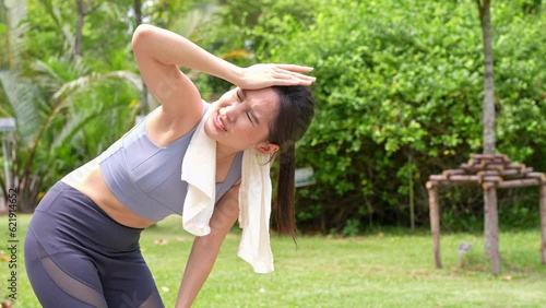 Sport asian woman gets tired and get dizzy, feel bad pain and suffer from heat stroke outdoors when jogging or exercise outdoor with strong sunlight in summer season. Heatstroke and heat wave concept.
