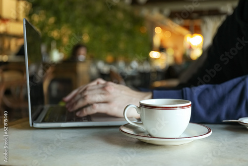 A cup of coffee on a table near a laptop in a cafe