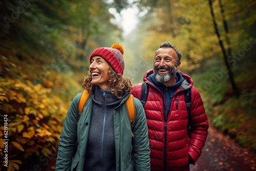 A photorealistic image of a couple of middle-aged hikers walking through an autumn forest in rainy weather. They happily communicate during their walk.